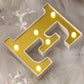 Gold 3D marquee letter "E" with warm white LED lights