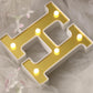 Gold 3D marquee letter "H" with warm white LED lights.