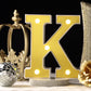 Gold 3D marquee letter "K" with warm white LED lights.