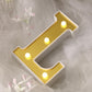 Gold 3D marquee letter "L" with warm white LED lights.