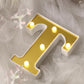 Gold 3D marquee letter "T" with warm white LED lights.