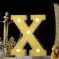 Gold 3D marquee letter "X" with warm white LED lights.