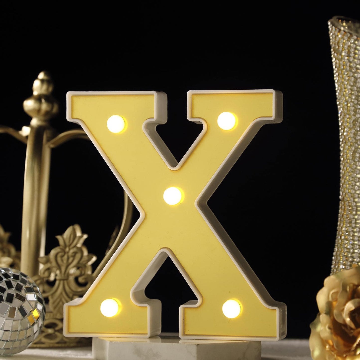 Gold 3D marquee letter "X" with warm white LED lights.