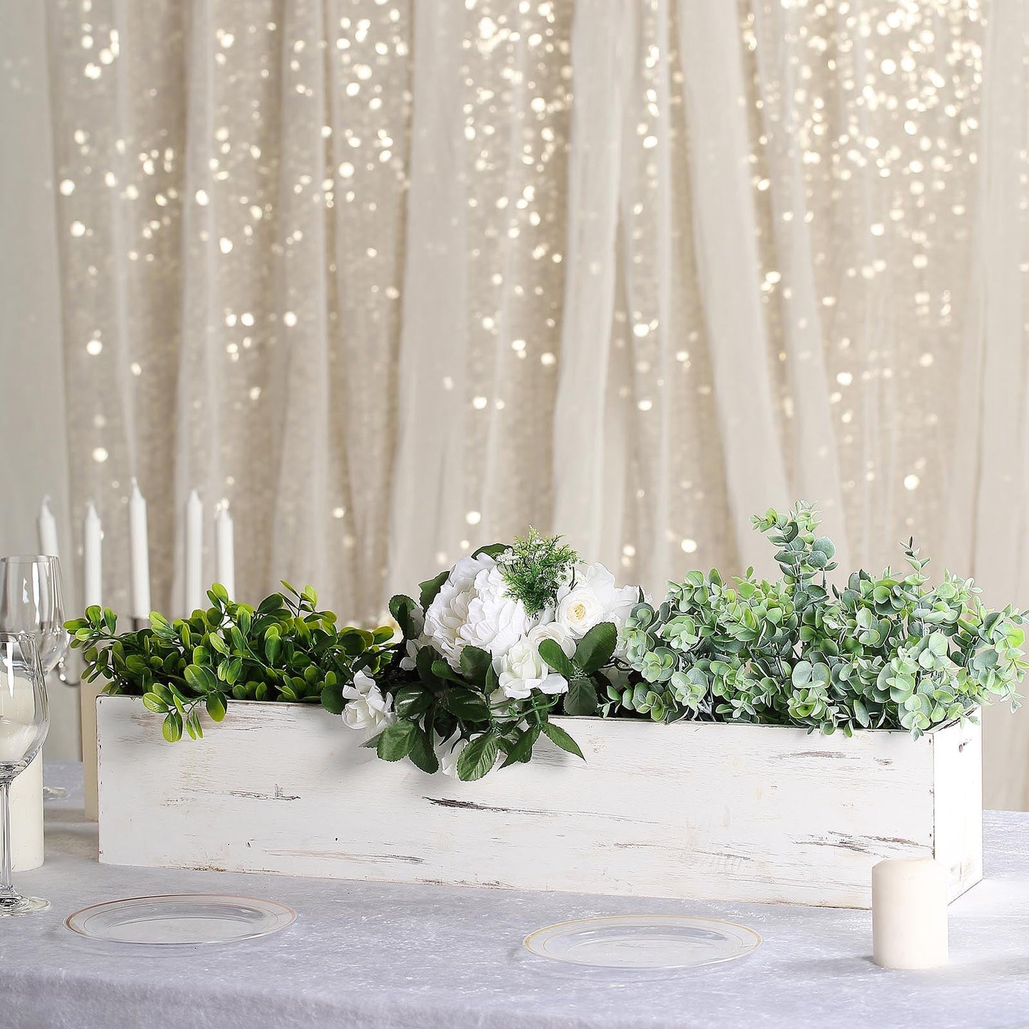 White rectangular wood planter box set with greenery and flowers.