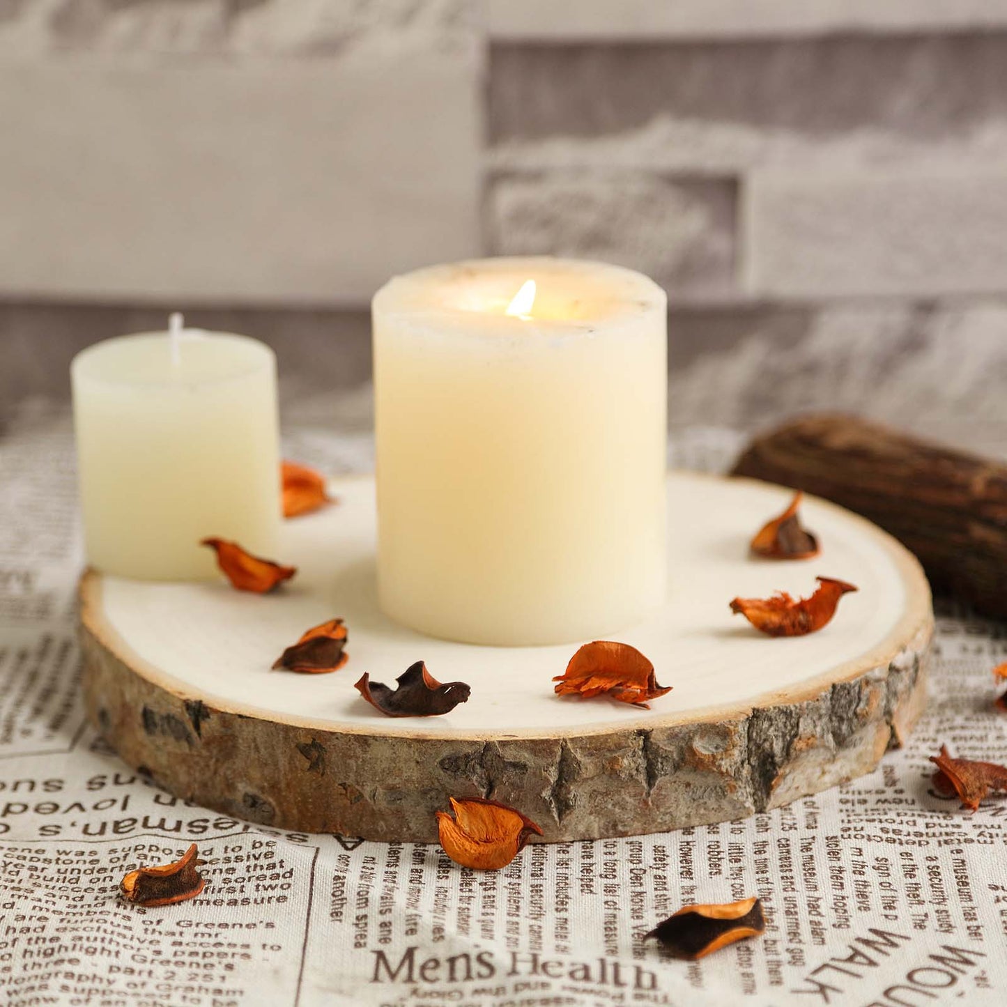 Rustic natural wood slice table centerpiece with candles and dried petals.