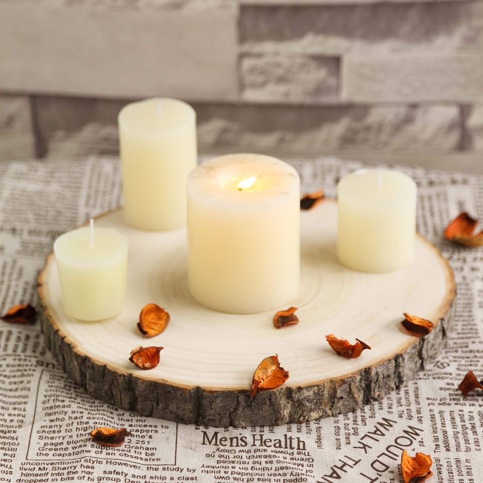 Round rustic wood slice centerpiece with natural color candles and dried petals.
