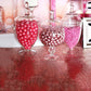 Clear apothecary glass jars with snap on lids, filled with pink candies.